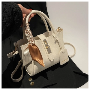 Détail du sac seau en cuir crème avec foulard en soie sur la poignée supérieure