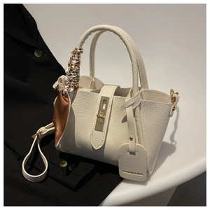 Détail du sac seau en cuir blanc cassé avec fermoir doré et foulard en soie pied-de-poule
