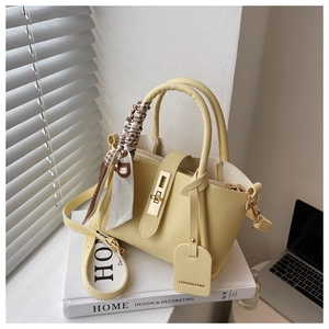 Détail macro du sac seau jaune à motif litchi avec foulard et fermoir doré