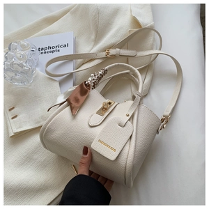 Détail du sac seau blanc en cuir avec poignée foulard sur un blazer blanc