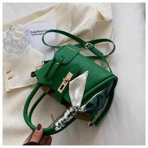 Détail du sac seau vert en cuir grainé avec fermoir doré et foulard en soie