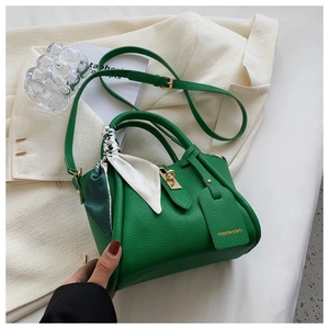 Détail du sac seau vert en cuir litchi avec fermoir doré et poignée ornée d'un foulard