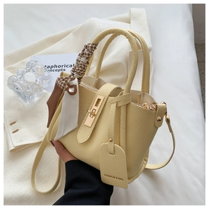 Détail du sac seau jaune en cuir avec foulard pied-de-poule et fermoir doré