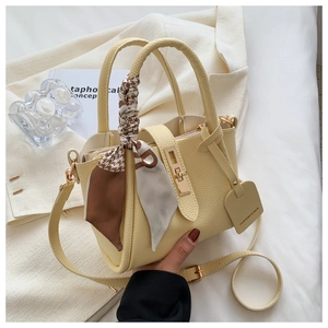 Détail du sac seau en cuir beige avec foulard décoratif et ferrures dorées