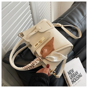 Détail du sac en cuir blanc cassé avec fermoir doré et poignée ornée d'un foulard en soie