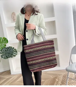 Ethnic style canvas tote bag with red and black stripes held by a model in a minimalist room