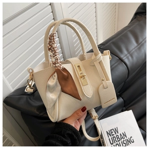 Détail du sac seau en cuir crème avec poignée en foulard de soie et fermoir doré