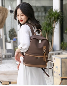 Detail of waterproof dark coffee nylon backpack with brown leather trim and silver zipper