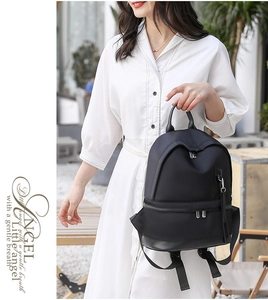 Close-up of black waterproof nylon backpack featuring metal zippers and leather handle