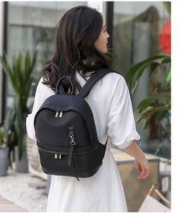 Detail of a black waterproof nylon backpack featuring metal rings and leather pullers