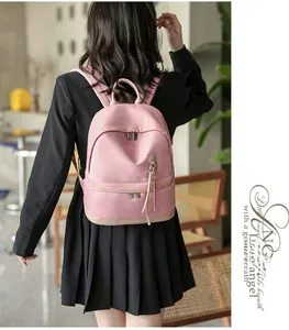Waterproof pink nylon backpack shown on model in a cozy indoor lifestyle setting
