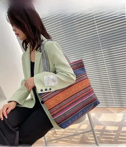Close-up of bohemian striped woven tote bag featuring striped handles and fabric patch detail