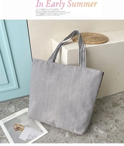 Close-up of minimalist gray canvas tote with striped handles in a sunny setting
