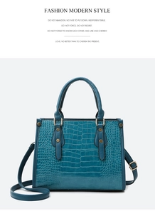 Detail of dark blue crocodile texture handbag with gold rivets and adjustable shoulder strap