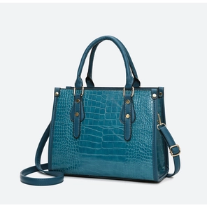 Detail view of dark blue crocodile pattern embossed handbag with gold rivet accents