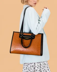 Détail d'un sac cabas marron à motif crocodile avec poignées noires et logo doré