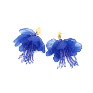 Dettaglio degli orecchini a fiore in resina blu con base dorata e nappe di perline