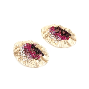 Detailed macro view of irregular oval earrings with colorful rhinestones on gold alloy