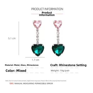 Close-up of pink and green crystal heart drop earrings with rhinestone chains