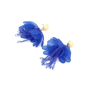 Dettaglio di orecchini floreali fatti a mano con petali blu satinati e nappine di perline