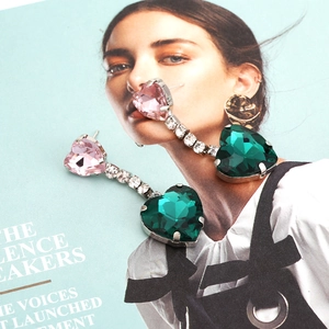 Elegant drop earrings featuring pink and green crystal hearts on a stylish magazine background