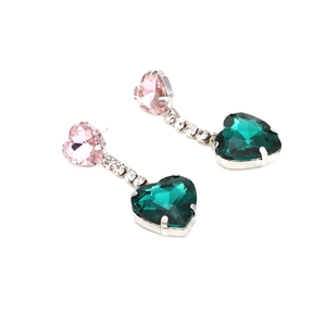 Detail of silver drop earrings with pink heart crystal and emerald green stone
