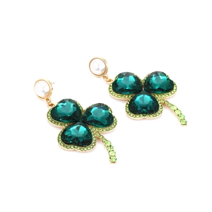Detailed view of gold clover earrings featuring emerald green heart crystals and small rhinestones