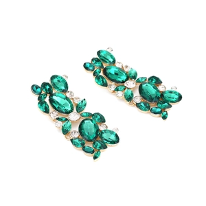 Close-up of vintage flower earrings with emerald crystals and gold alloy setting
