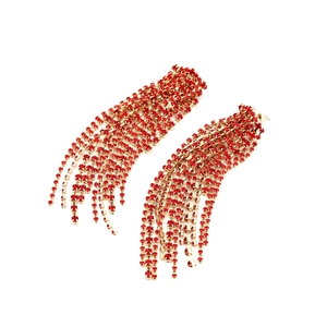 Close-up of long tassel earrings featuring vibrant red rhinestones on gold-tone claw chains