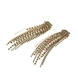 Macro view of long gold tassel earrings with dark green rhinestones in a cascade design