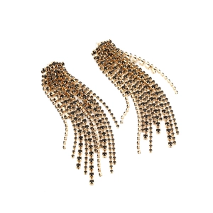 Close-up of long gold fringe earrings with shimmering black rhinestones and tassels