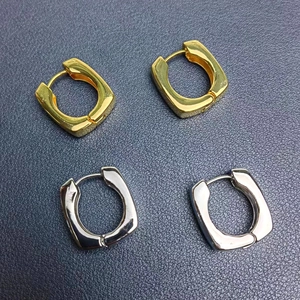 Détail des boucles d'oreilles géométriques carrées en métal poli doré et argenté