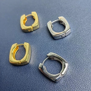 Gros plan de boucles d'oreilles créoles carrées dorées et argentées au fini poli