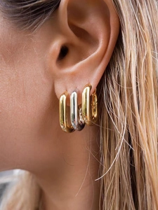 Gros plan de boucles d'oreilles créoles dorées et argentées en forme de U sur un mannequin