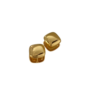 Macro shot of minimalist square gold stud earrings with polished metallic surface finish