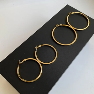 Macro detail of four polished gold hoop earrings with flat edges on black display