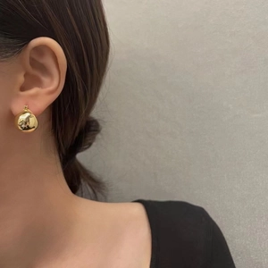 Close-up of minimalist 18K gold plated irregular ball stud earrings on a model's ear