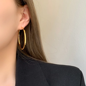 Close-up of oversized polished gold hoop earrings with a sleek mirror finish on model