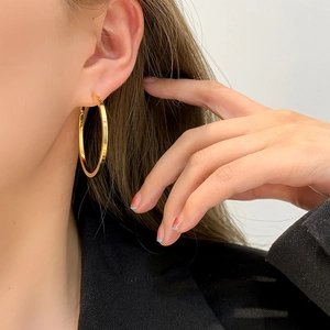 Polished gold large hoop earrings shown on model wearing a black blazer