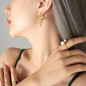 Boucles d'oreilles lave dorées irrégulières et bagues serties sur un mannequin
