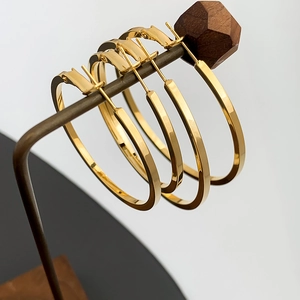 Detailed view of three pairs of large golden hoop earrings with polished metal finish
