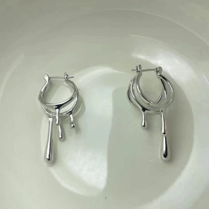 Détail des boucles d'oreilles irrégulières en lave argentée avec texture métal liquide