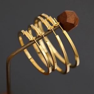 Close-up of two pairs of polished gold hoop earrings hanging on a metal display stand