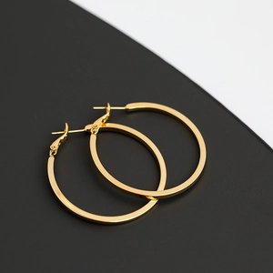 Detailed view of polished golden square hoop earrings on a black and white background