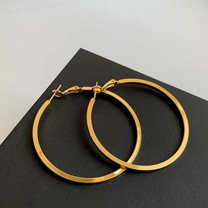 Detailed view of polished gold hoop earrings with secure clasp on a display stand
