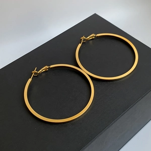 Detailed view of large gold hoop earrings with mirror finish on a black jewelry box