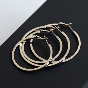 Close-up of four polished silver-tone large hoop earrings with flat surface design