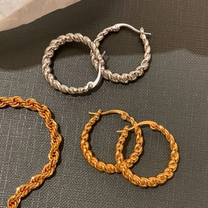Flat lay of gold and silver twisted hoop earrings with matching rope chains on dark texture
