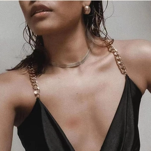 Detail of 18K gold-plated C-shape earring paired with a chic chain-strap satin top