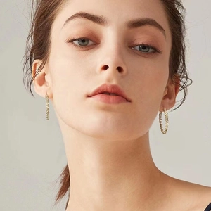 Gros plan de créoles dorées avec texture grainée scintillante portées par un mannequin